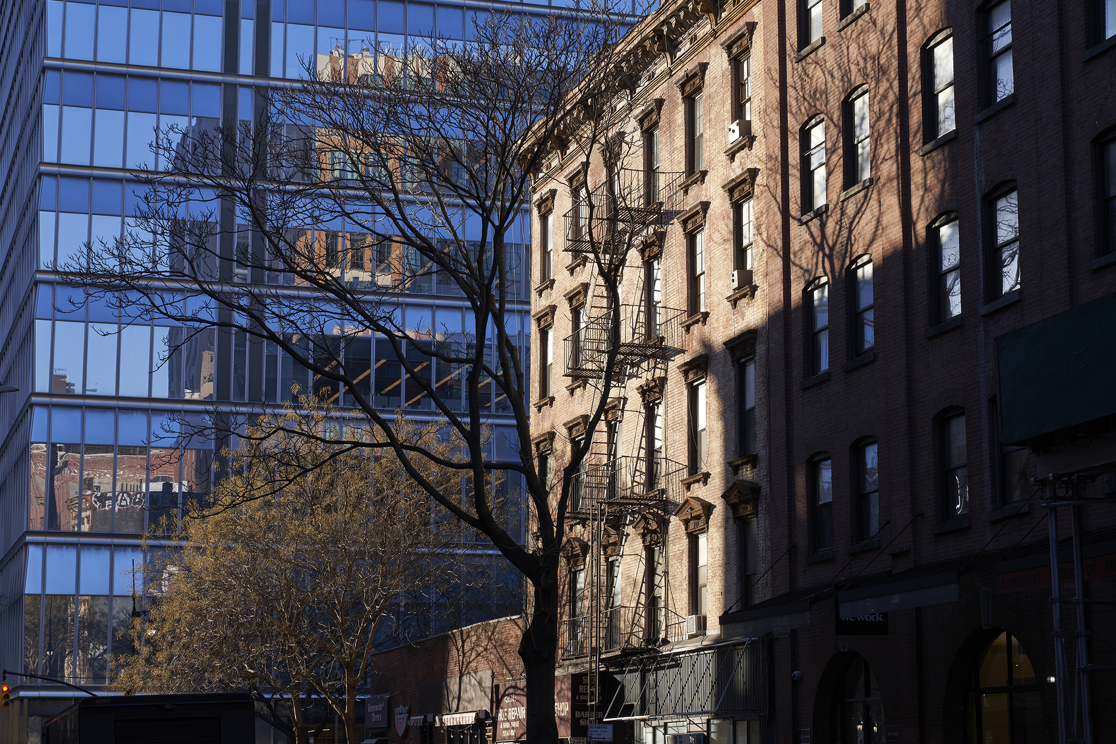 A redbrick warehouse building sits next to a modern glass and concrete building in Tribeca, New York